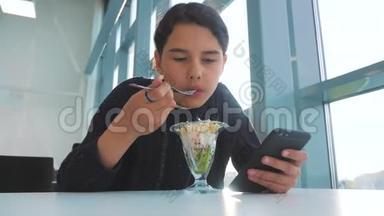机场等待飞机航班.. 十几岁的女孩吃沙拉，看上去像智能手机。 咖啡馆里的网络生活方式。 机场